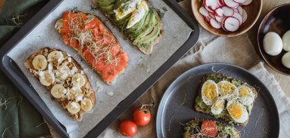 A variety of savory and sweet toasts with avocado, banana, eggs, and fresh toppings on a wooden table.