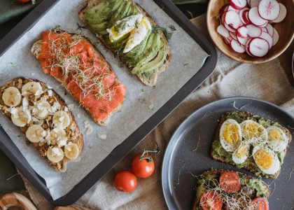 A variety of savory and sweet toasts with avocado, banana, eggs, and fresh toppings on a wooden table.