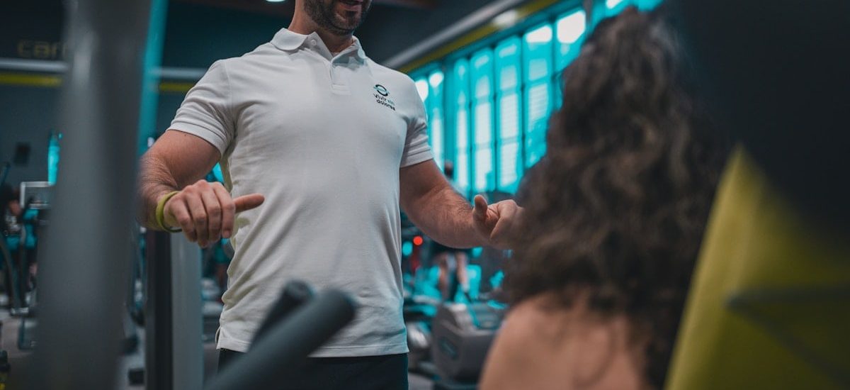 Sesión de entrenamiento en el gimnasio con un entrenador personal, enfocada en el rendimiento y el bienestar físico.